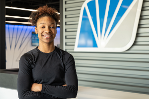 Image of teenager girl standing with arms crossed in lobby of a credit union