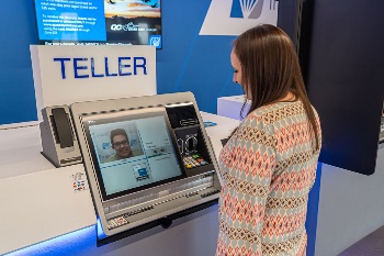 Woman standing ITM with man on screen