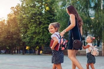 Mom and young daughters walking to school