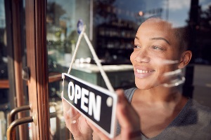 Women behind glass turning over the open sign