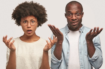 Couple with a questioning look on their faces and their hands up