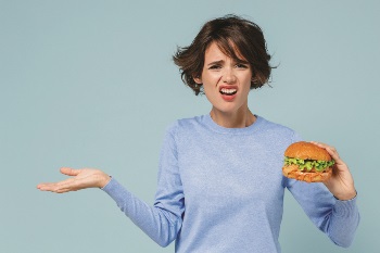 Girl holding a sandwich looking perplexed