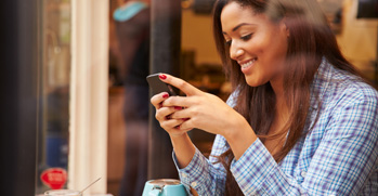 Woman looking at her phone and smiling in a storefront window