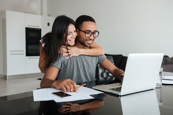 Wife hugging husband looking at computer