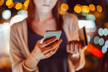 woman holding credit card and cell phone